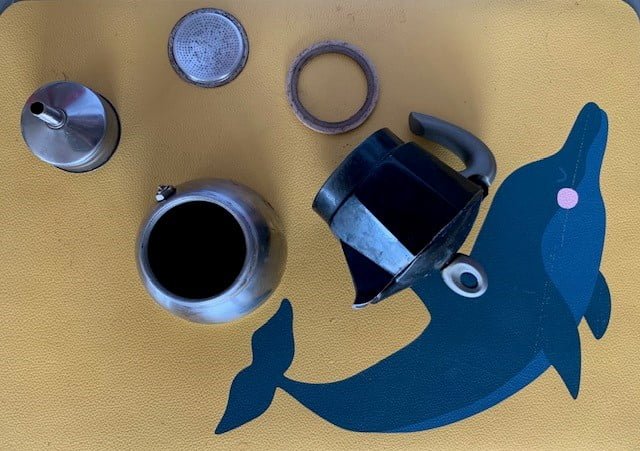 Moka smontata. Sono visibili e i vari pezzi di una moka: caldaia, raccoglitore, guarnizione, filtro, dosatore caffè